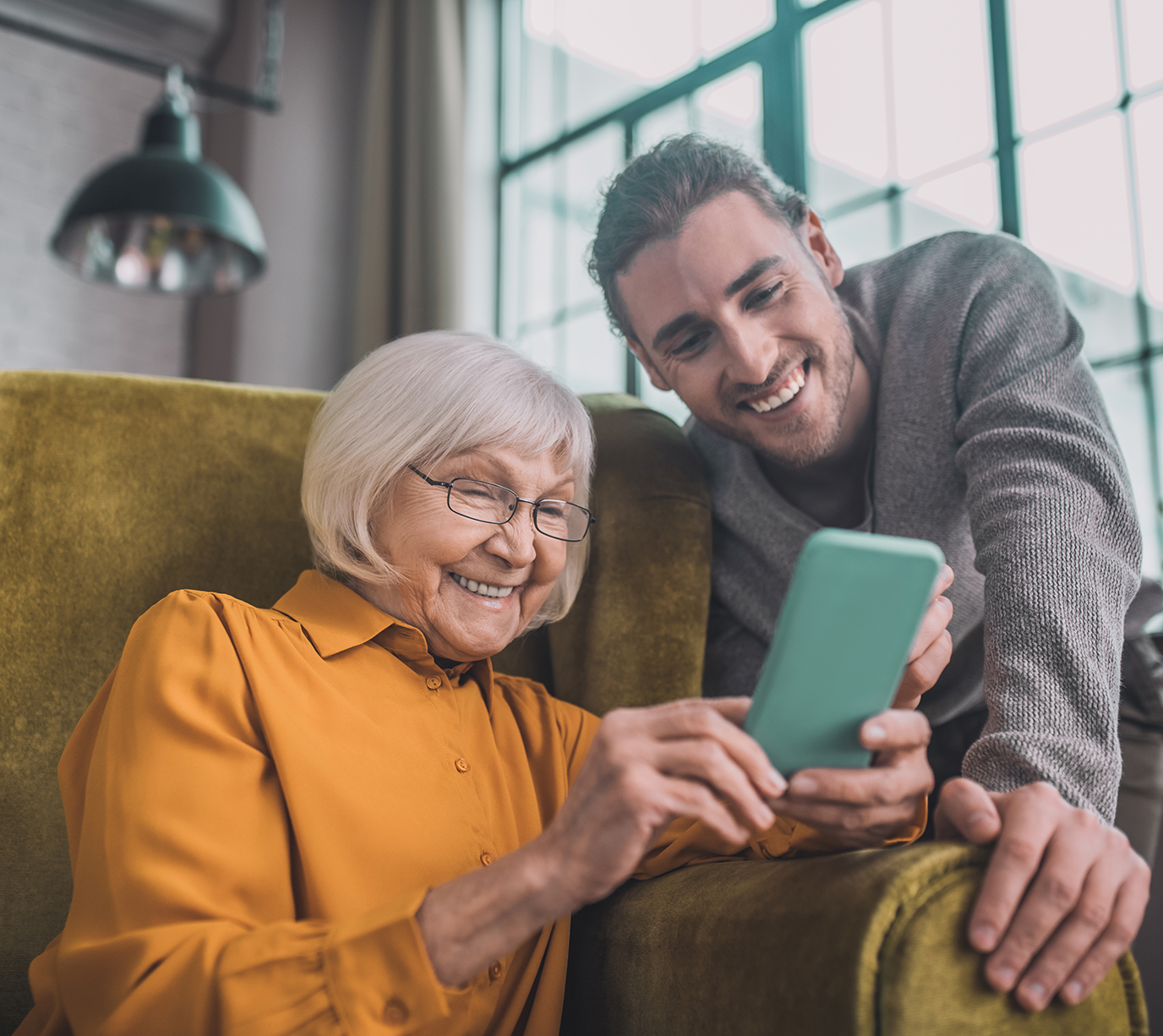 donna anziana che mostra smpartphone a un uomo giovane