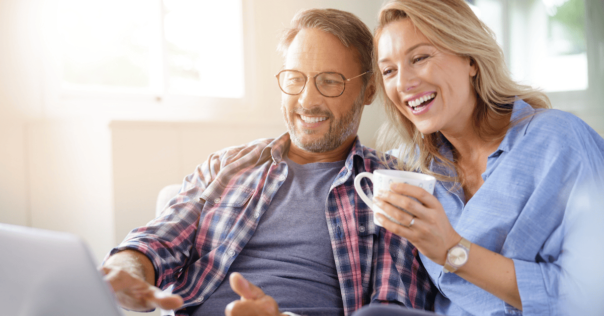 Uomo e donna di 50 anni che ridono guardando il computer