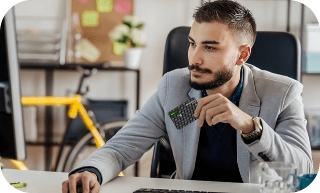 Un uomo seduto a un desk, con in mano una carta di debito, mentre lavora su un computer