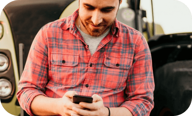 Un uomo sorride mentre tiene in mano un cellulare.