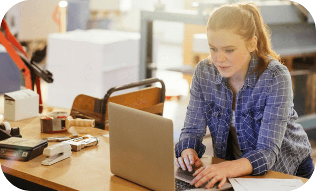 Una donna utilizza un laptop, immersa nel suo lavoro tra attrezzature industriali