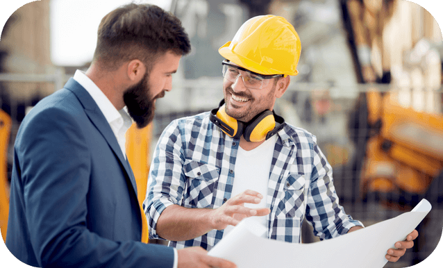 Due uomini con caschi discutono piani di lavoro.