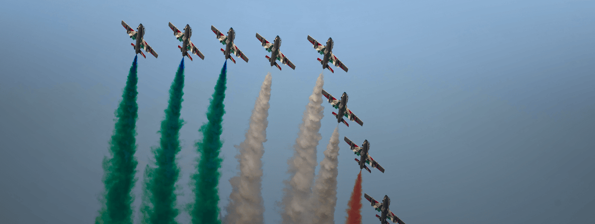 Un gruppo di aerei in formazione con scie di fumo tricolore