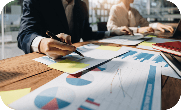 Team di lavoro composto da uomini e donne impegnati in un progetto, con grafici e materiali di lavoro visibili.