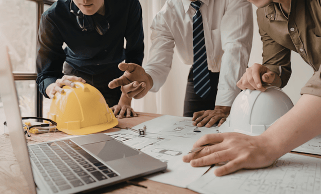 un gruppo di persone attorno a un computer che elaborano piano industriali