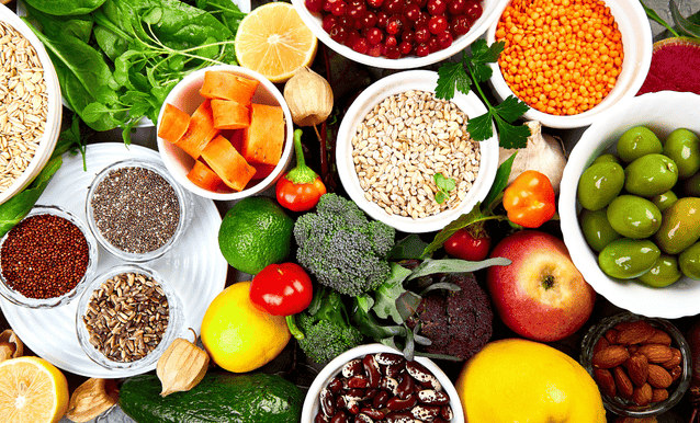 Una varietà di frutta e verdura disposta in ciotole colorate su un tavolo.