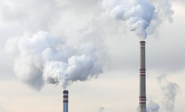 Due camini industriali che emettono fumi