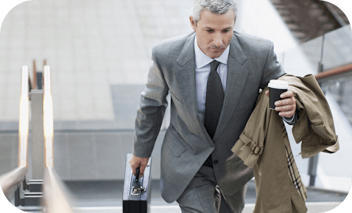 Un uomo in giacca e cravatta sale le scale con passo deciso.