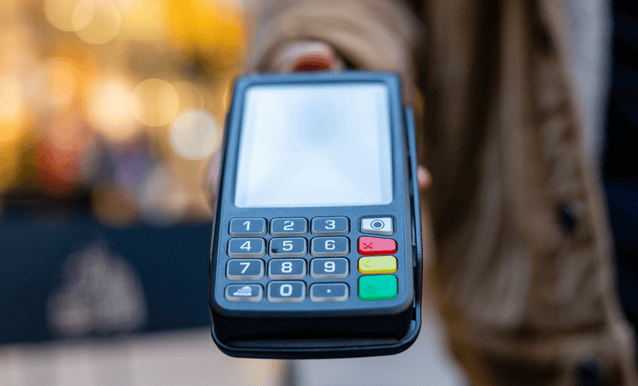 Una persona porge un POS per i pagamenti con carta