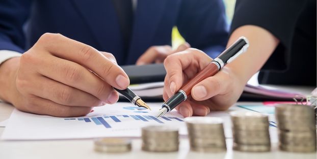 Persone che analizzano documenti, con monete a disposizione, evidenziando l'importanza economica.