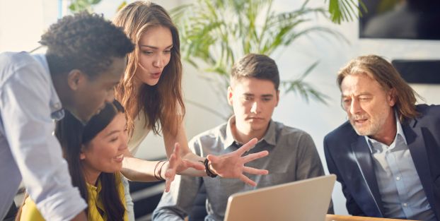  Persone riunite attorno a un laptop per confrontarsi su temi di economia di base.