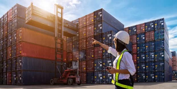 Donna con elmetto che indica container per attività di esportazione.