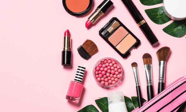 Trucchi e prodotti cosmetici disposti su una superficie rosa