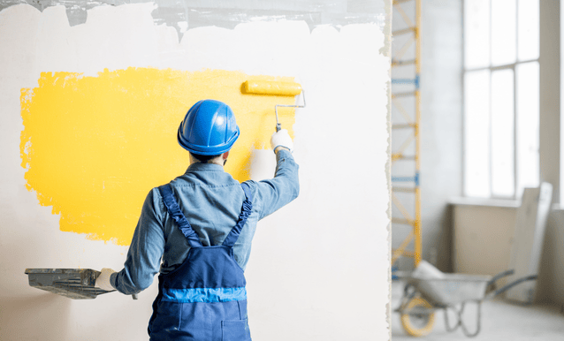 Uomo che dipinge la parete interna di una casa in costruzione