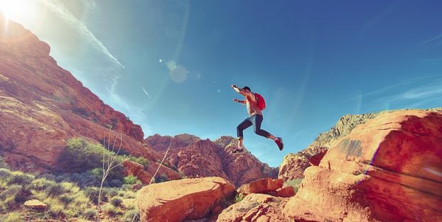  Un uomo che salta tra le rocce nel deserto, rappresentando il simbolo del rischio.