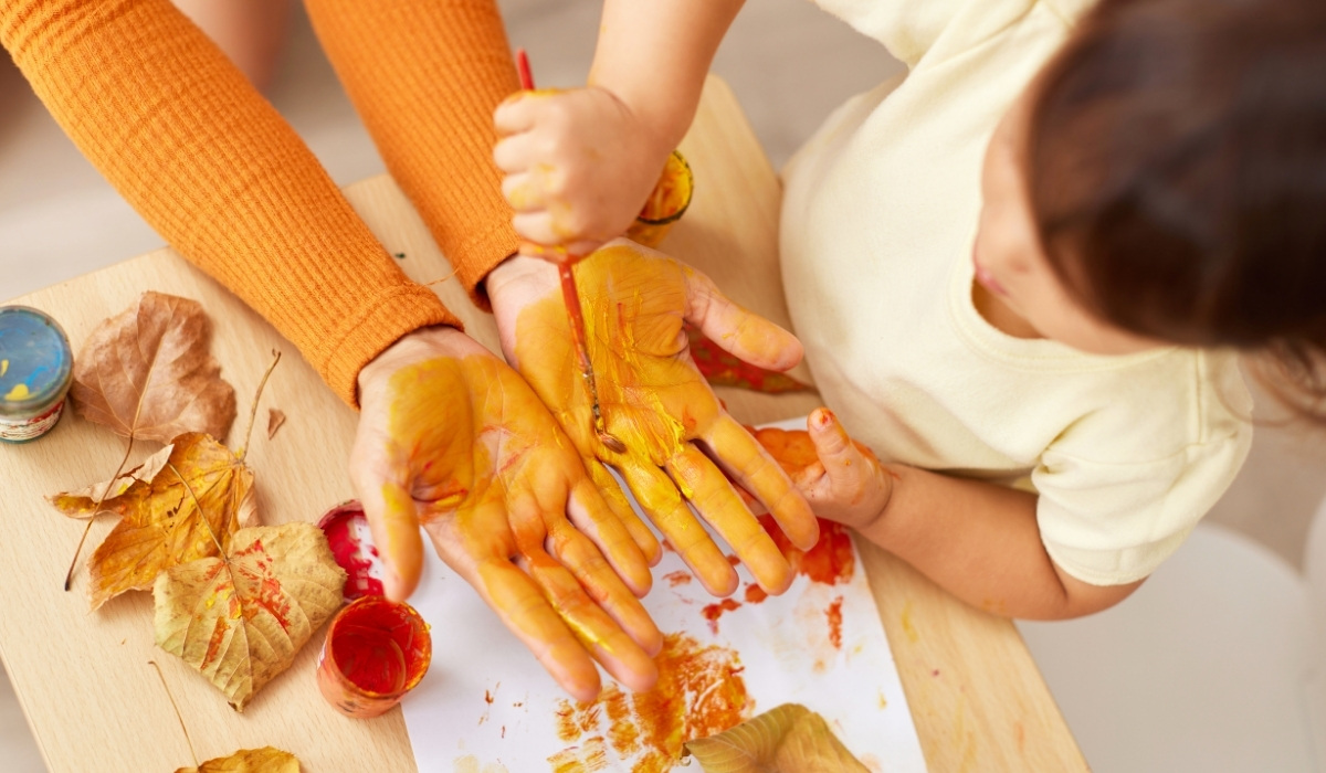  Mani di genitore dipinte da colore a tempera giallo per mano di una bambina