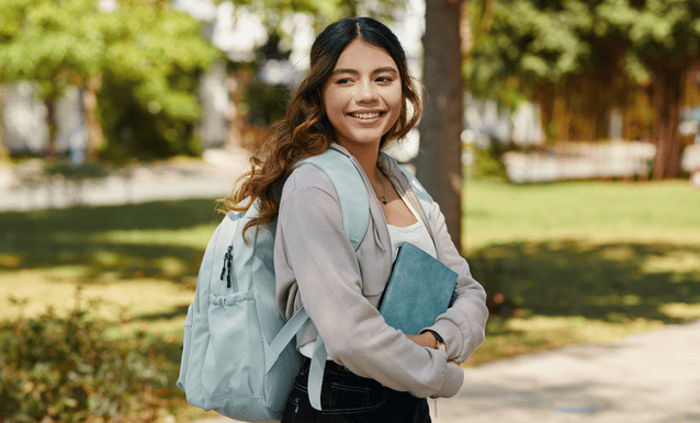studentessa che ha in mano dei libri, con sullo sfondo un giardino