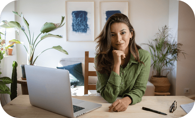 Donna sui 30 anni seduta a un tavolo, lavora al laptop in un ambiente domestico.