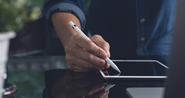 Un uomo vestito elegantemente con in mano un tablet e una penna touch screen sta firmando un documento 