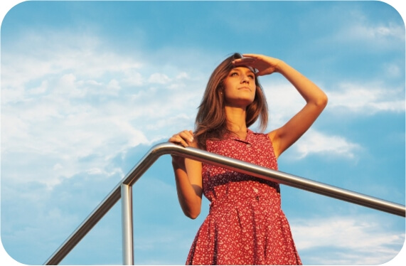 Una ragazza giovane che guarda l’orizzonte coprendosi dal sole evidenziando come sia importante pensare alla soluzione previdenziale più adatta