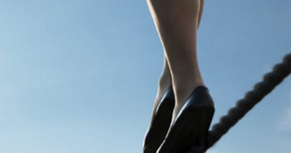 Le gambe di una donna in tacchi che camminano su una fune in equilibro mettendo alla luce l’importanza della normativa europea sulle crisi bancarie detta Bail-in
