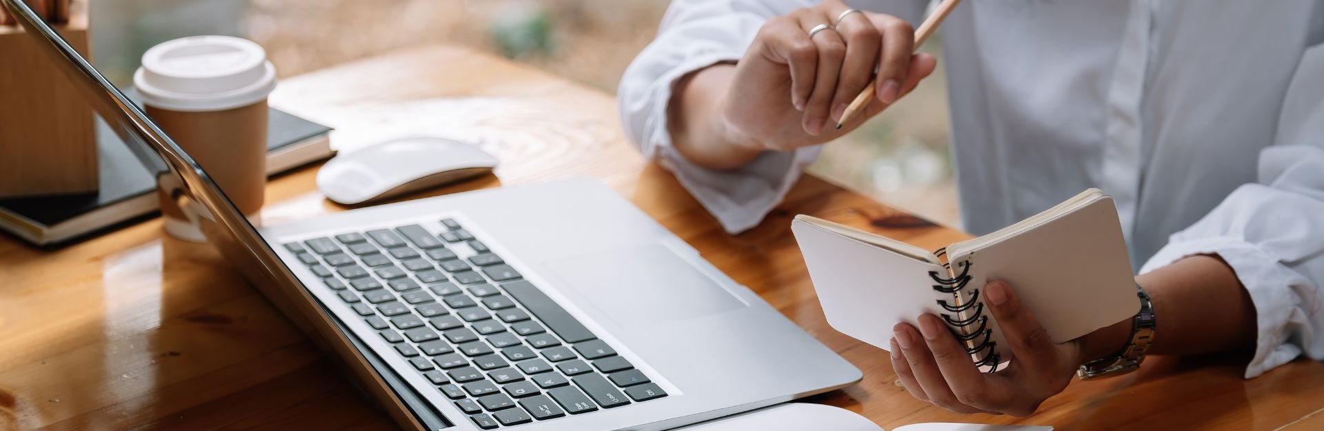 Donna davanti ad un laptop che prende appunti su un block notes
