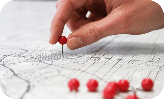 Una persona mostra una mappa con diversi pin rossi.