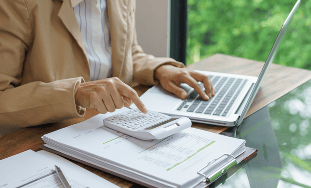 Una donna utilizza un laptop e una calcolatrice per gestire i suoi conti.