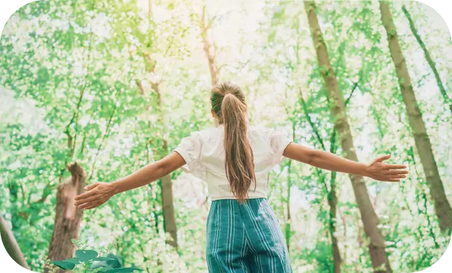 ragazza che apre le braccia verso il cielo in una foresta o bosco