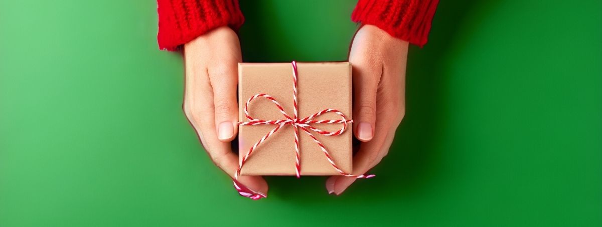 Mani che stringono un pacco regalo 