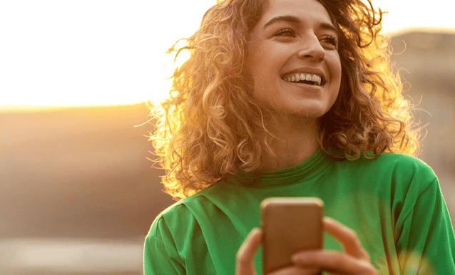 ragazza che sorride con un telefono in mano