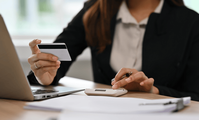 Una donna con un laptop in una mano e una carta di credito nell'altra