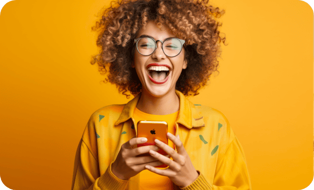 Sfondo arancione con una ragazza giovane vestita completamente di arancione, in mano un cellulare arancione e una risata euforica perché ha scoperto il prestito a lei dedicato.