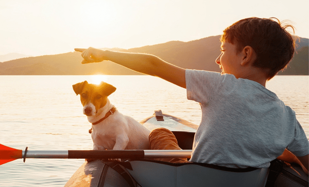  Un bambino in canoa insieme a un cane, immersi nella natura e circondati da un paesaggio sereno