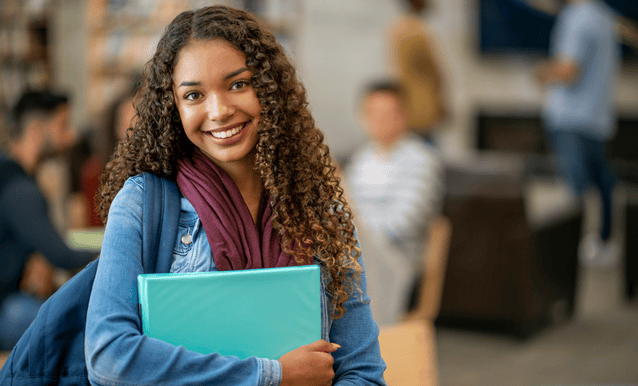 giovane studentessa con dei libri in mano e uno zaino in spalla