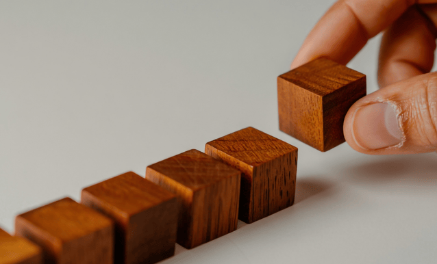 una mano che mette in fila dei dadi di legno