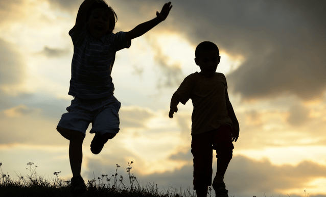 due bambini in ombra che giocano in un prato