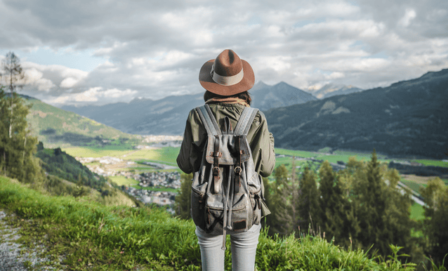 ragazza con uno zaino in spalla che guarda il panorama di una valle