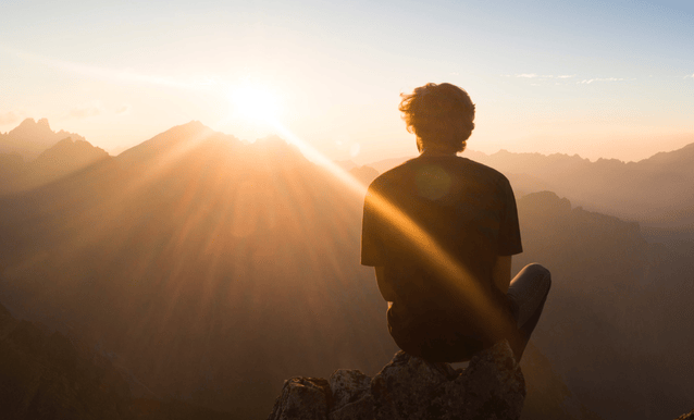 persona seduta su una roccia che guarda l'orizzonte