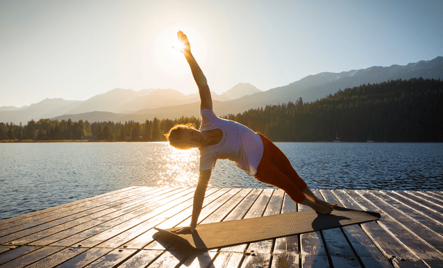 ragazza che pratica yoga vicino ad un lago al tramonto
