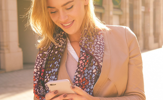 Donna che guarda il suo cellulare per capire con l’app Mutuo Credem come stia procedendo la sua pratica.