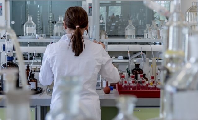 Operatrice dell'associazione italiana linfomi in camice da laboratorio, al lavoro su un progetto scientifico.