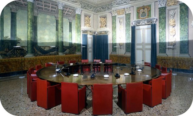 Salone delle feste con affreschi in verde e tavolo rotondo con sedute rosse