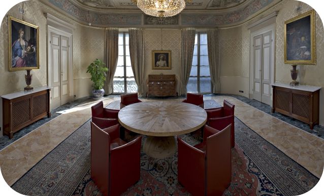 Sala da pranzo in stile baracco di Seicento e Ottocento, con tavolo ovale e sedute rosse in pelle in primo piano.
