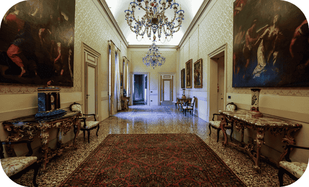 Corridoio del palazzo settecentesco con grandi lampadari in cristallo e dipinti antichi alle pareti